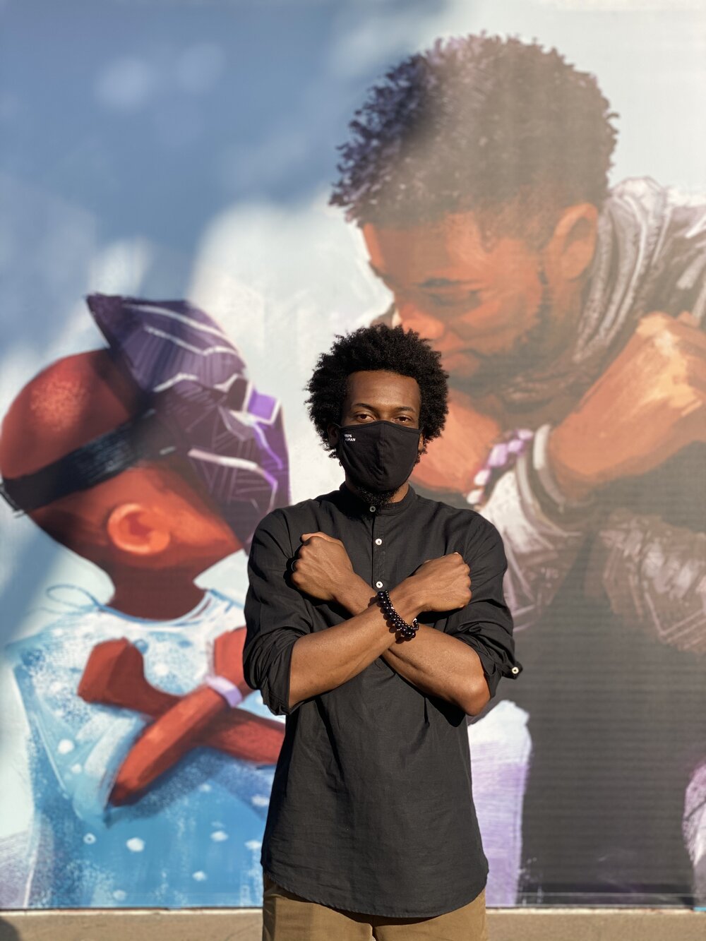 Nikkolas Smith stands in front of his illustration honoring Chadwick Boseman, now a mural at Downtown Disney