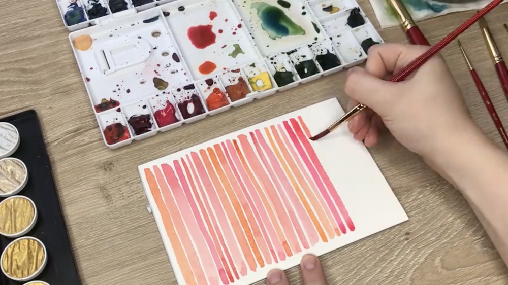Skillshare instructor Caitlin Sheffer demonstrates making watercolor lines on a piece of paper—a beautiful example of creative self care.
