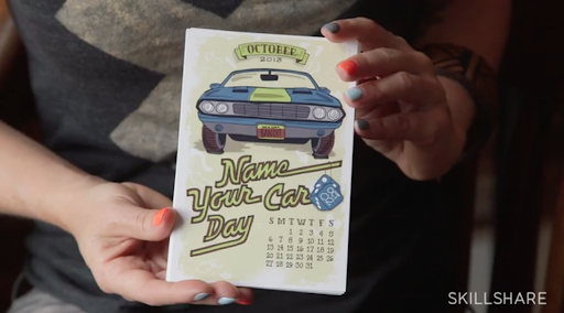 Skillshare instructor Annica Lydenberg holds up an illustration of a calendar that includes hand-lettered writing.