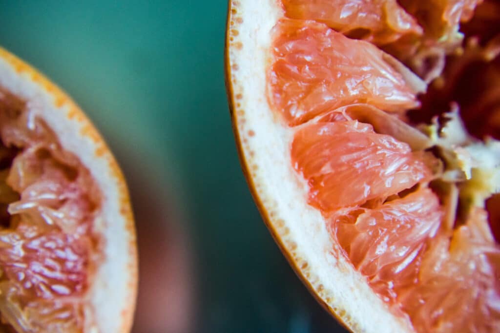 A close-up photo of the edge of a squeezed grapefruit half against a green background.