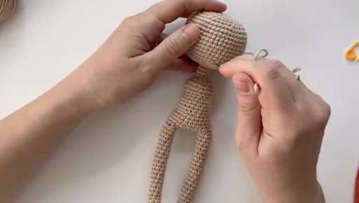 Hands holding amiguri doll half finished.