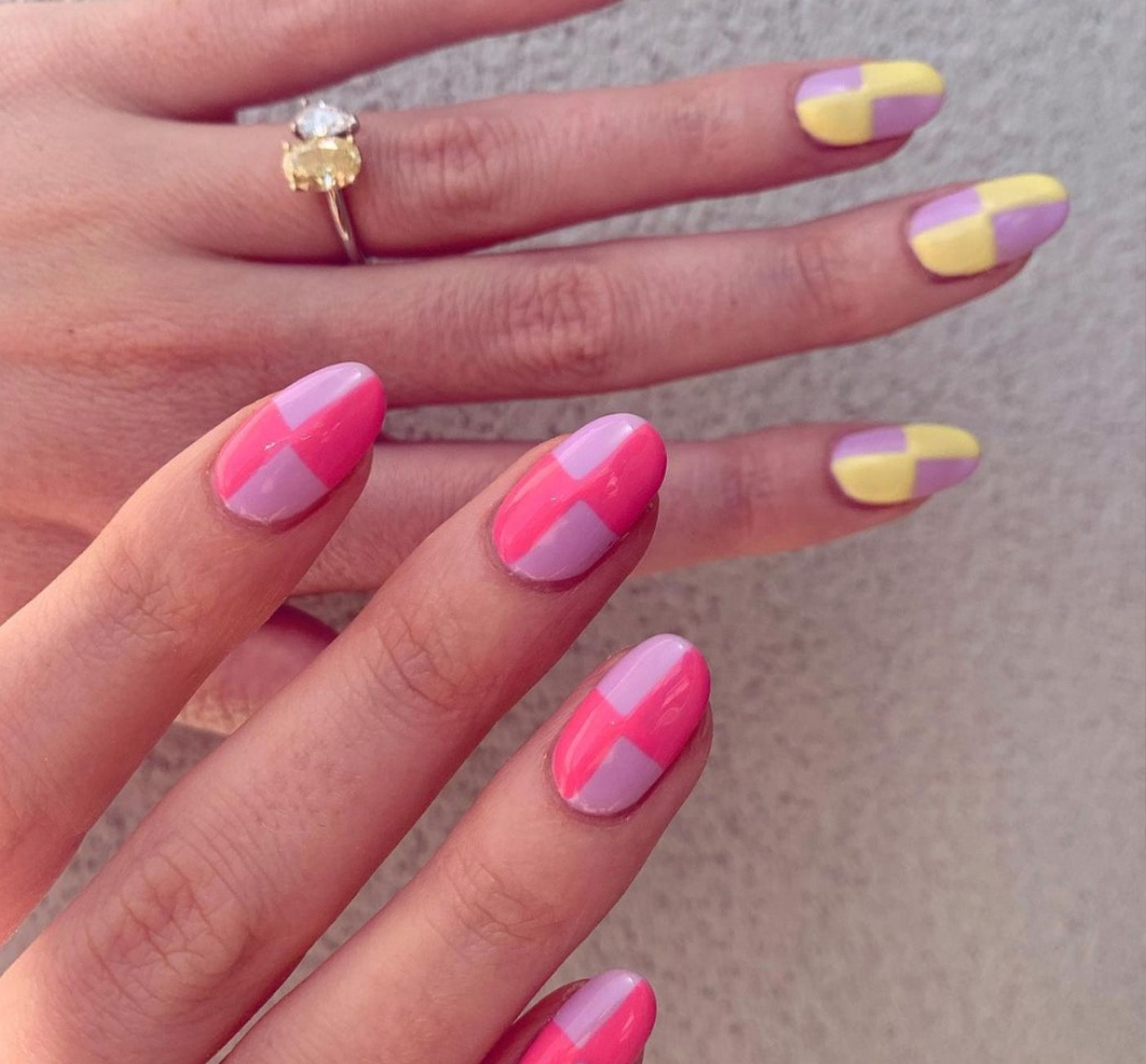 Hands with painted checker nails. One hand is yellow and pink checkered nails and the other is two tone pink checkered.