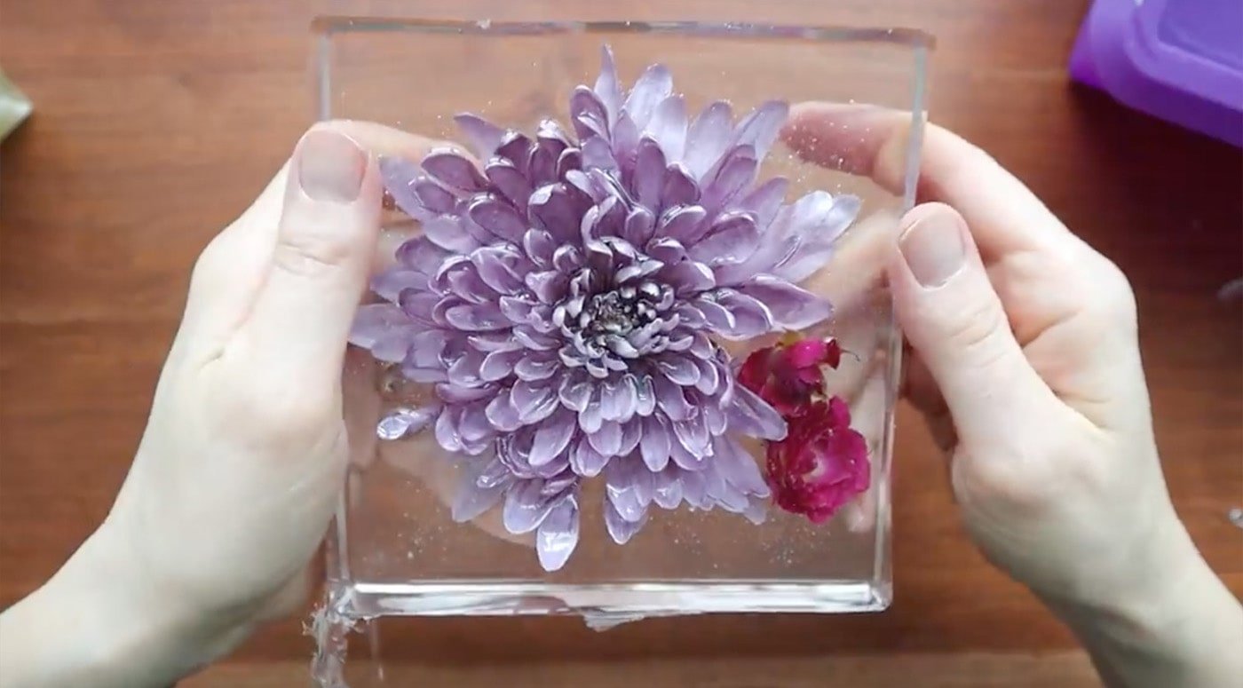 large purple flower suspended in resin square.