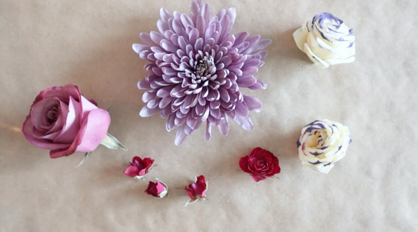 Rose, purple flower, white flower, and little red flowers on a table top