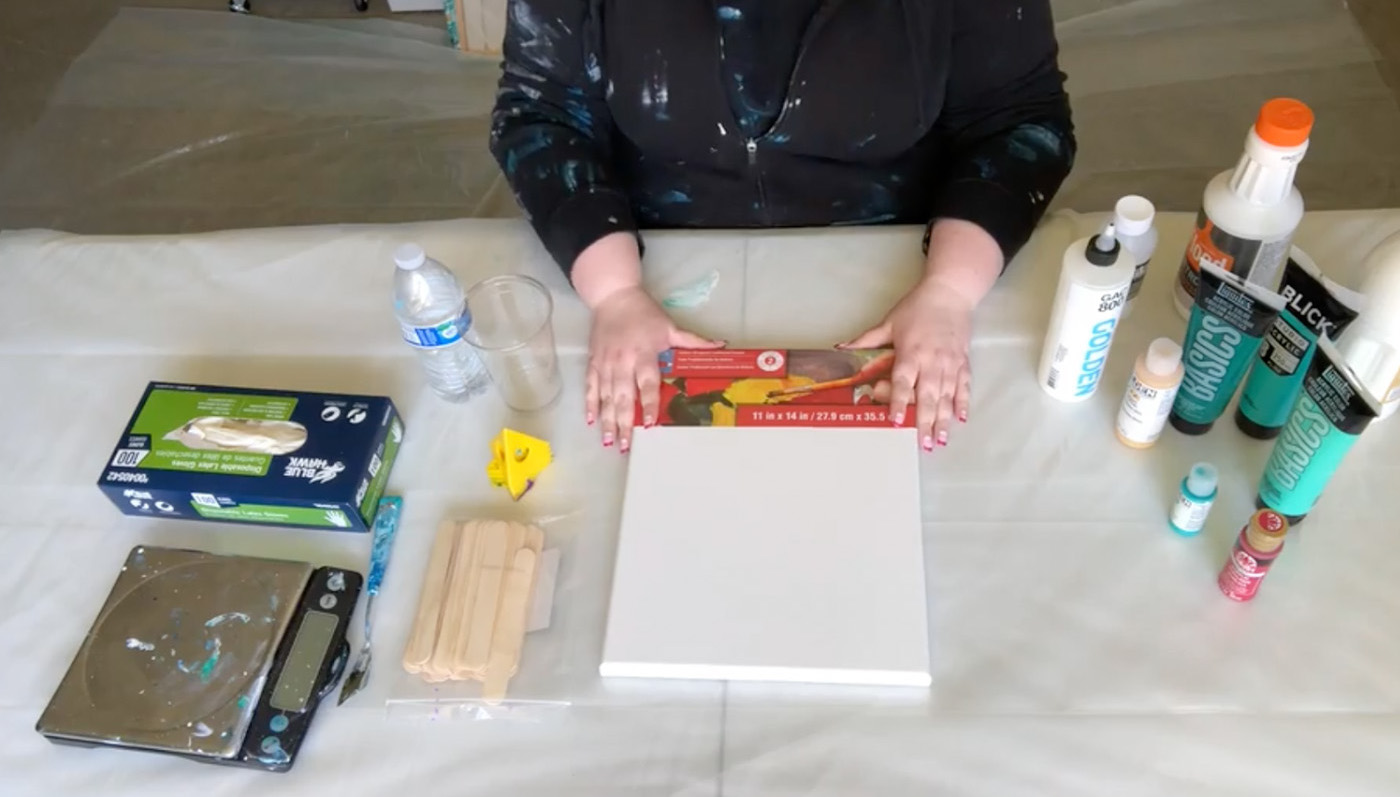 Table with gloves, scale, scaple, popsicle sticks, water, canvas, and various paints.