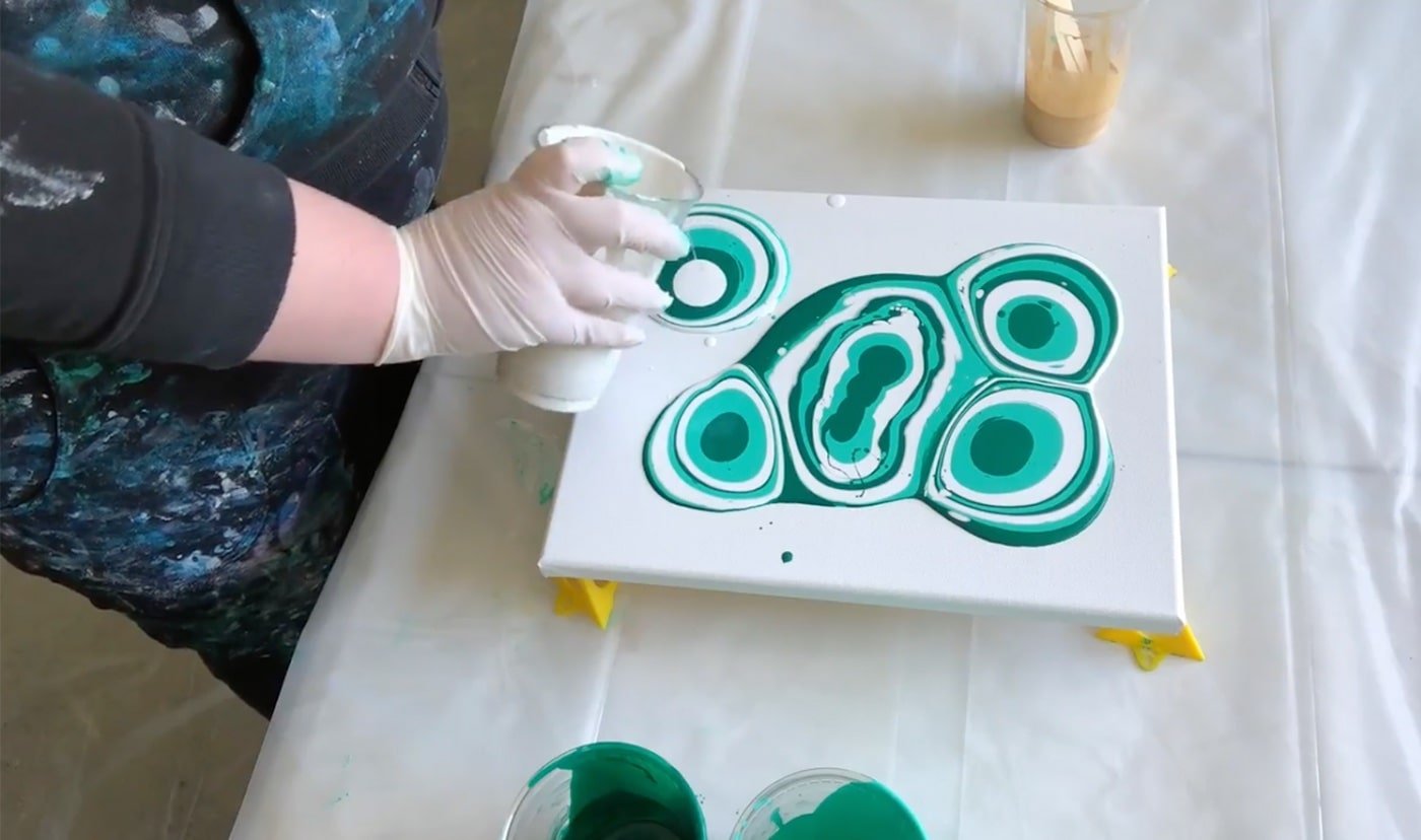 Pouring the paint in concentric circles in random places on the canvas.