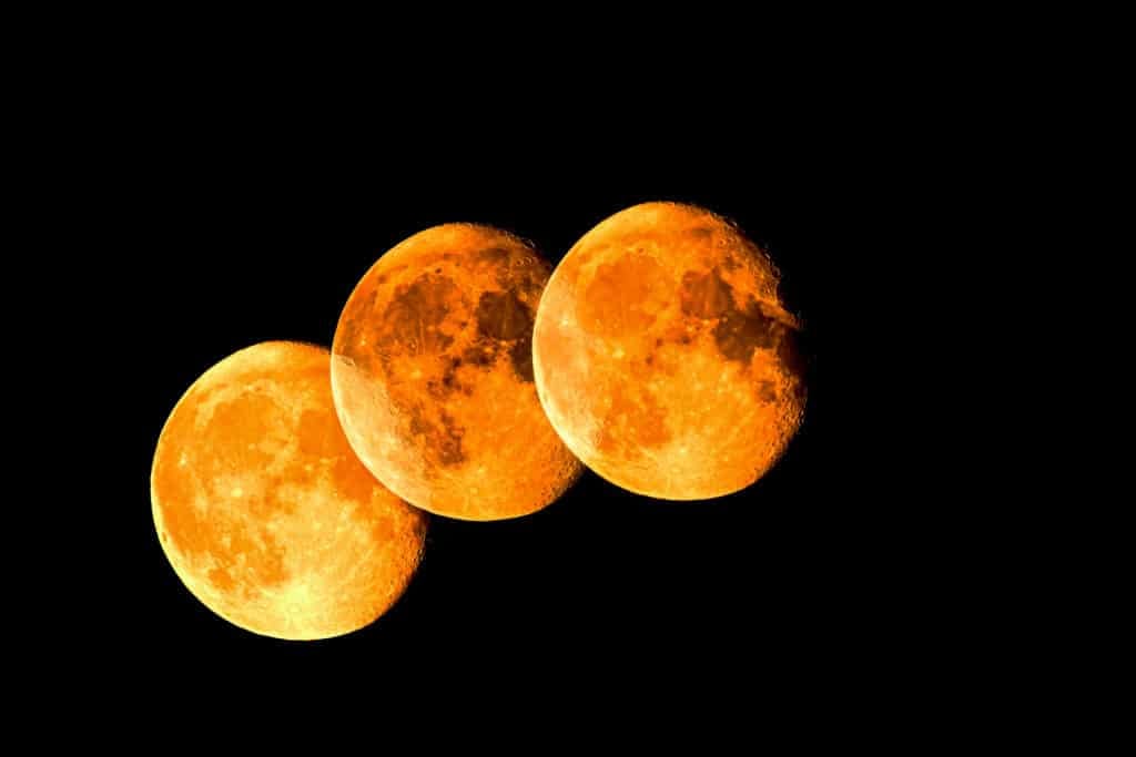 Black background with three overlapping, time-lapse images of an orange colored moon