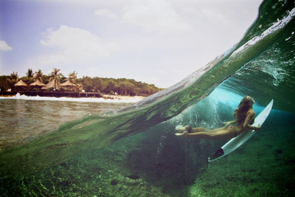 The top left half of the photo shows the sky and the shoreline. The bottom right corner shows a surfer underwater, diving under a wave.