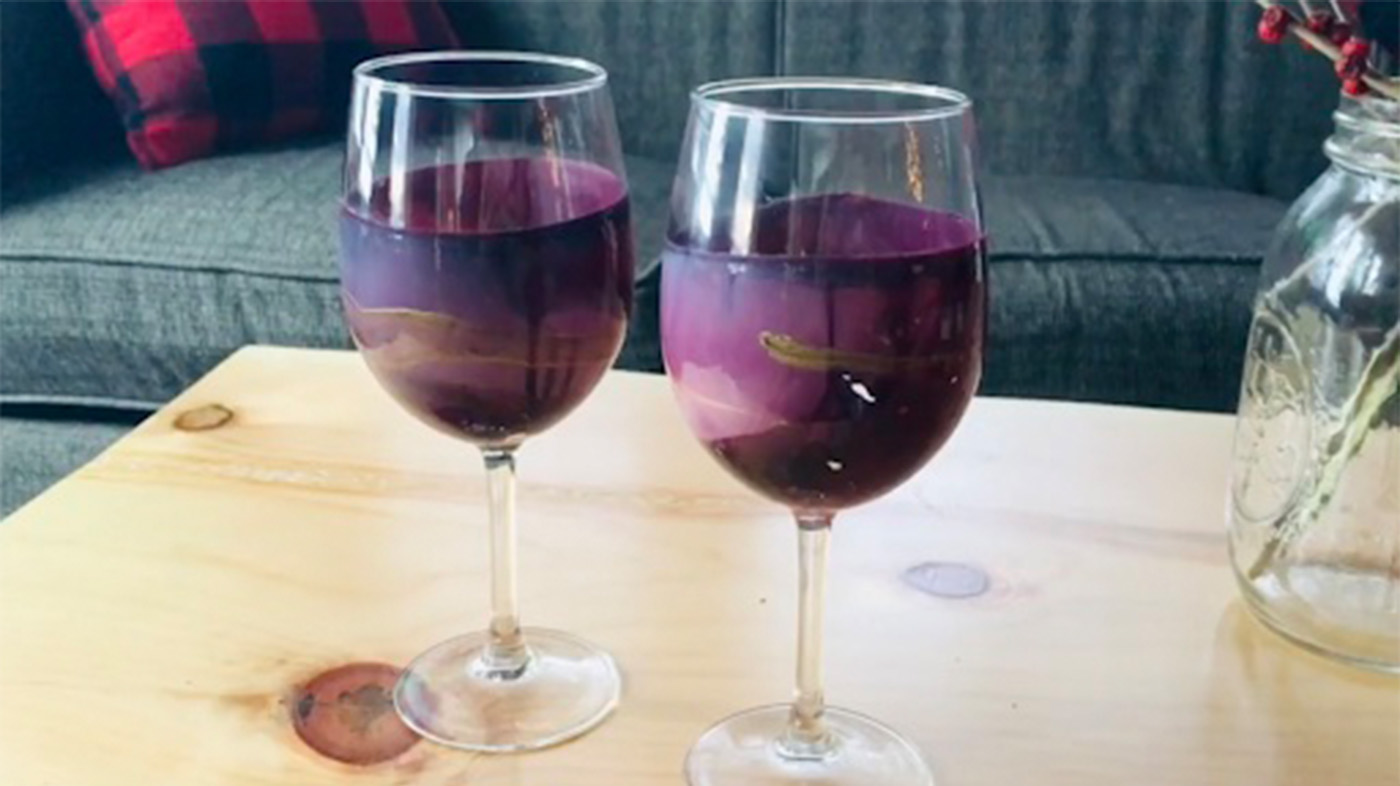 Dried purple and gold paint in two wine glasses sitting on a table in front of a couch.