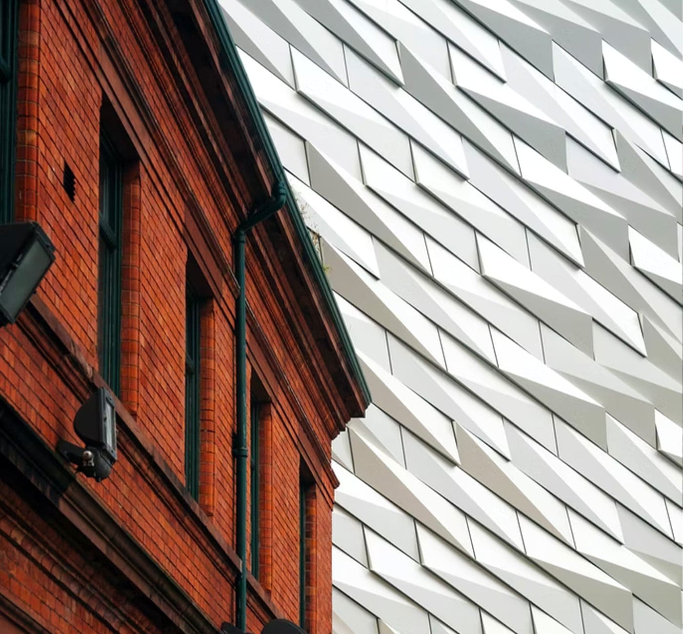 White modernist geometric building contrasts with an old red brick building.