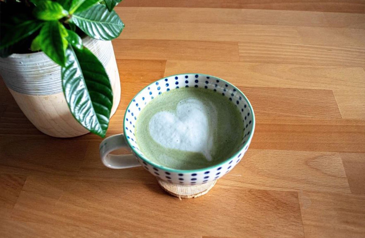 Cup of matcha latte with heart in drink.