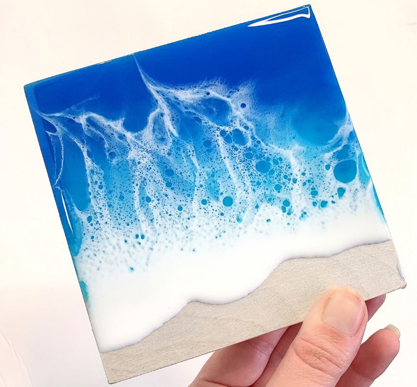 Resin coaster painted to look like rolling waves on a beach