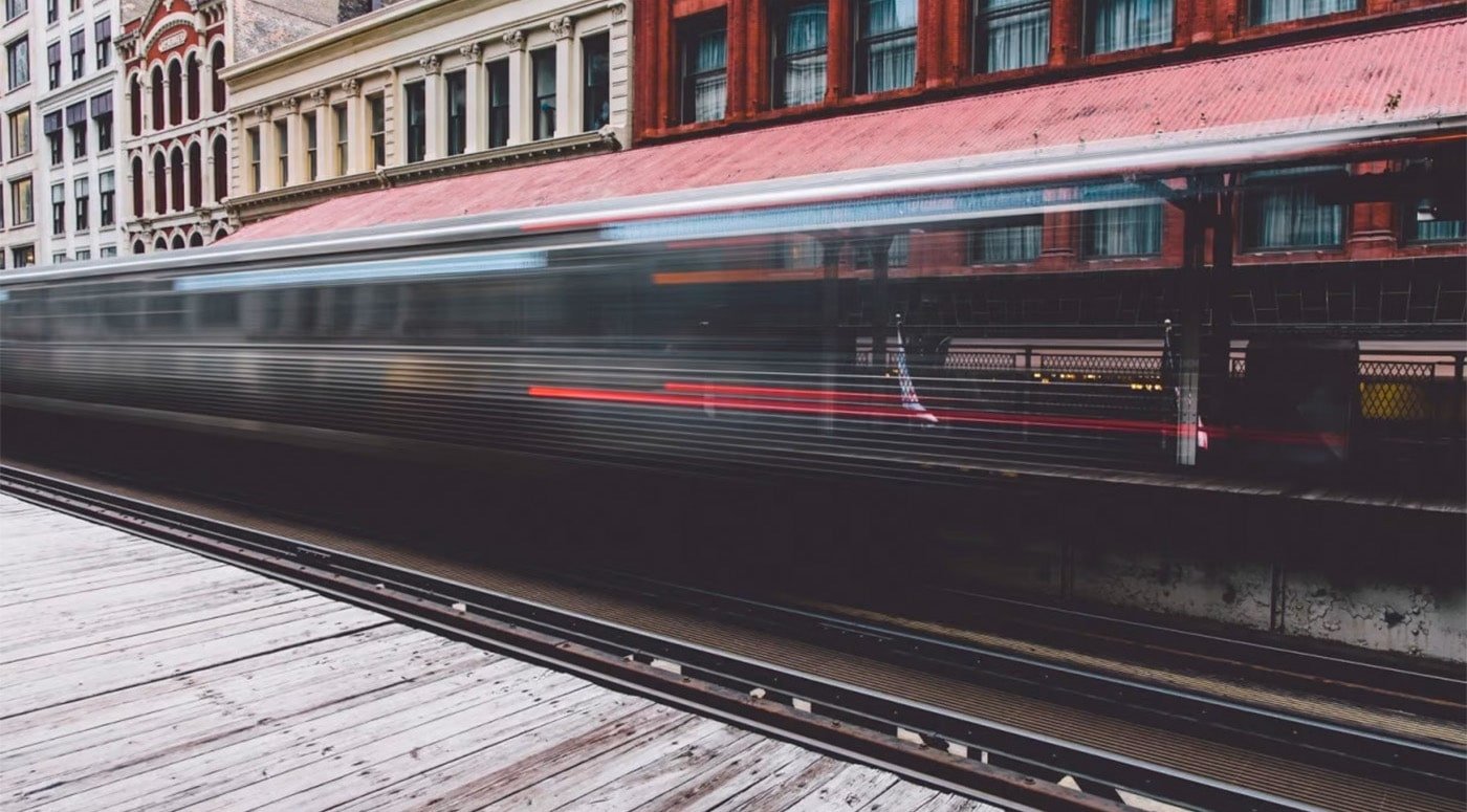 Long exposure photo where train is just a blur but behind it are really old town houses.