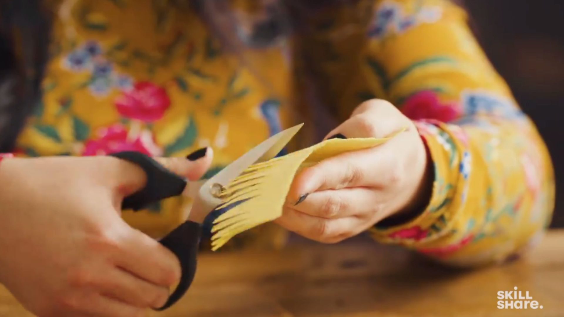 Person cutting a fringe design into crepe paper.