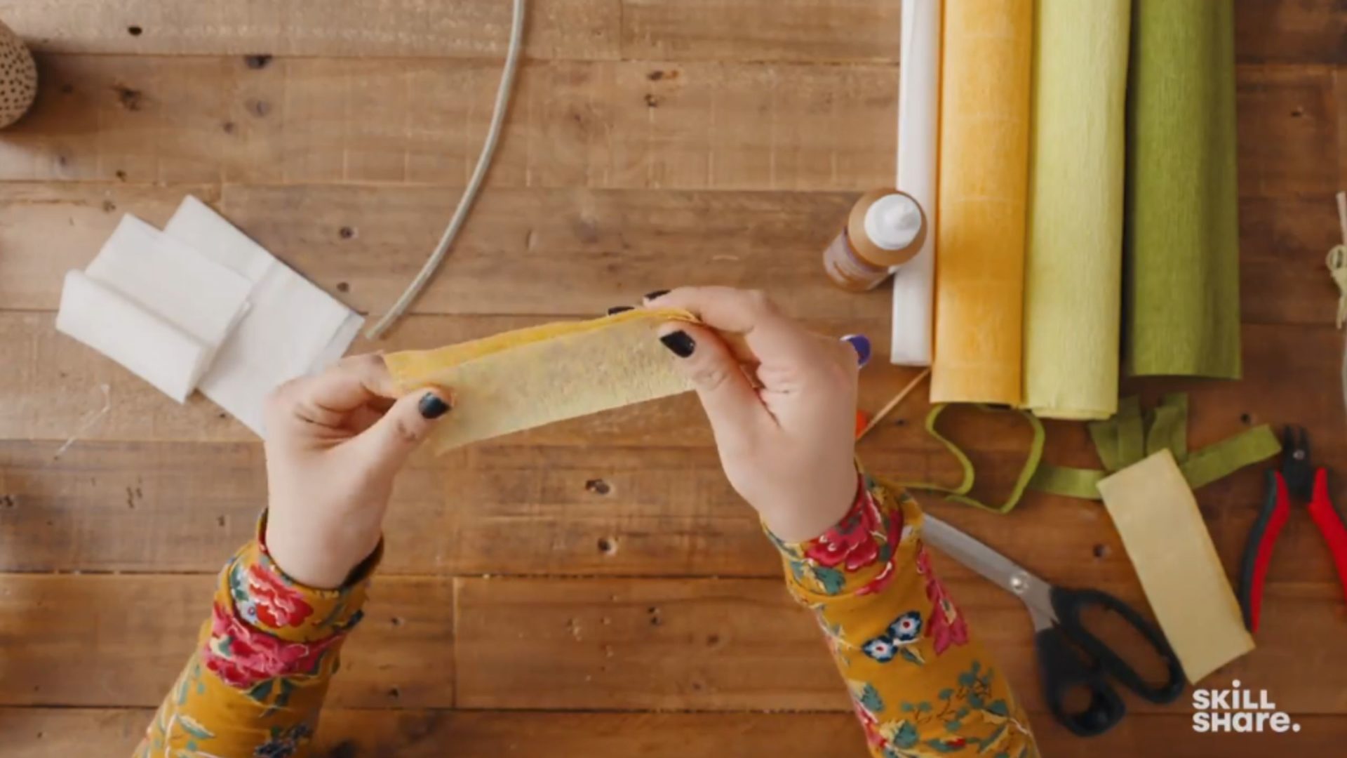 Crafter pressing three pieces of pale colored crepe paper together.