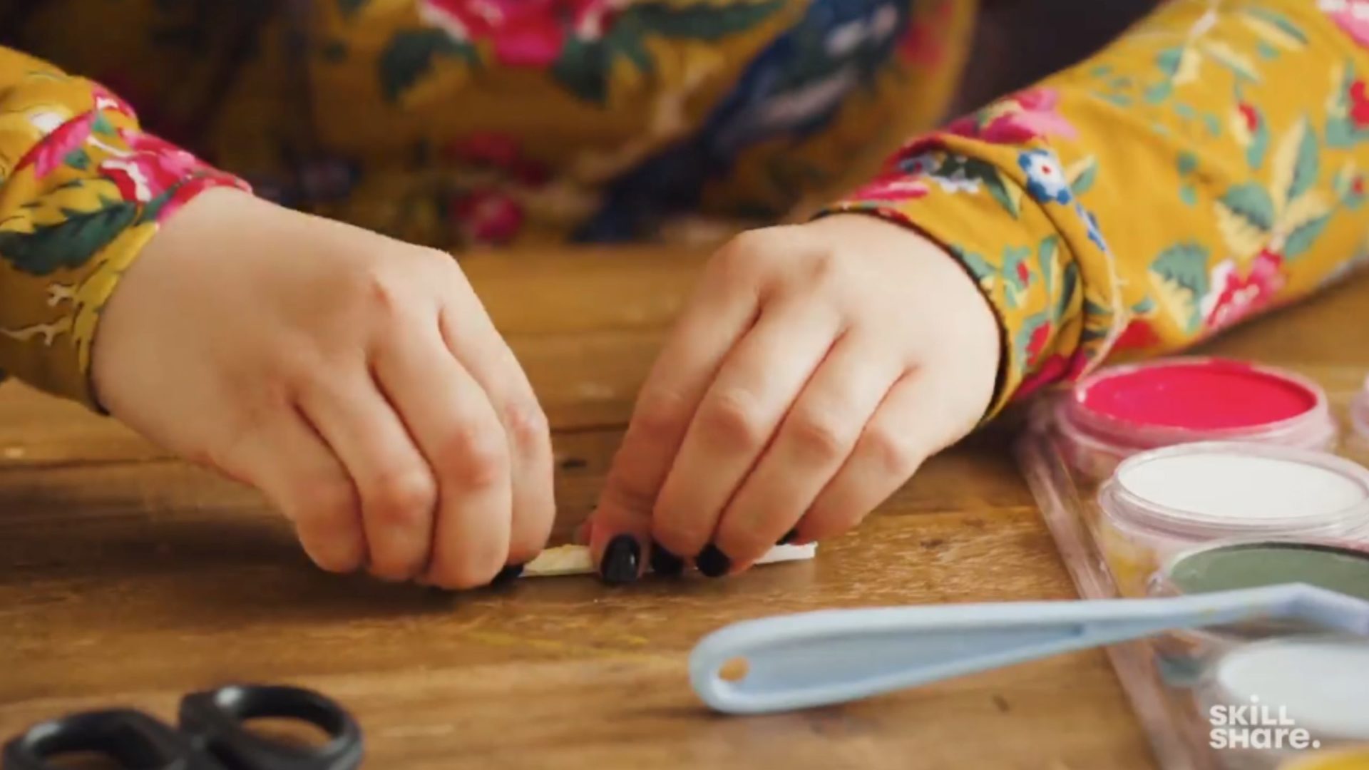 Crafter rolling crepe paper into a thin line with an accordion fold.