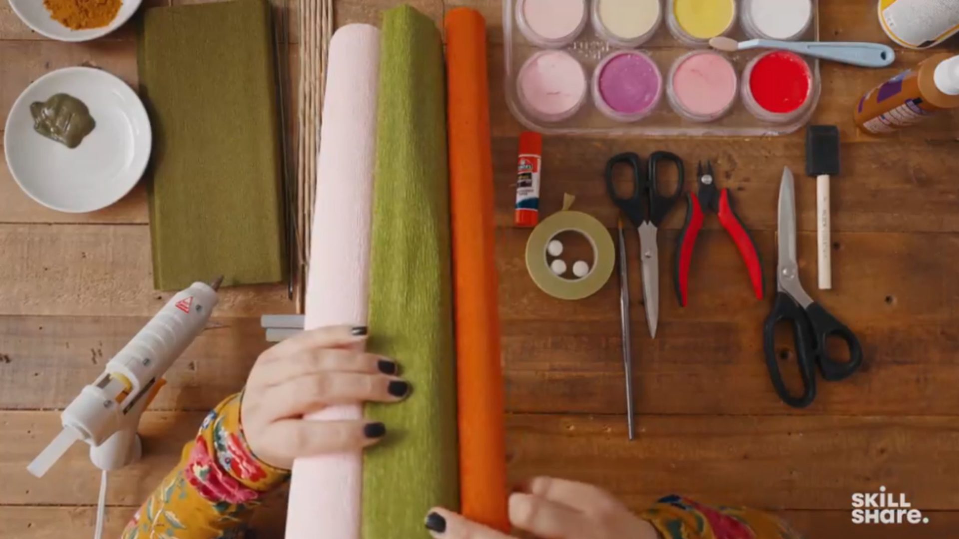 Crepe paper, scissors, paint, and other crafting tools on a wooden desk