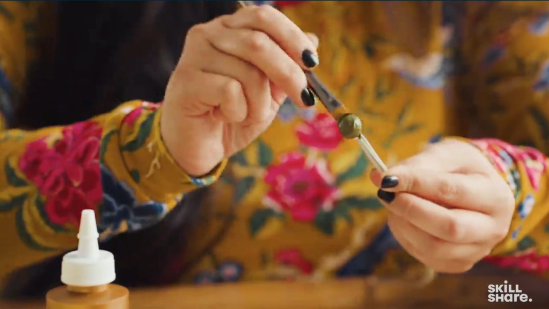 Person painting a small cotton ball green.