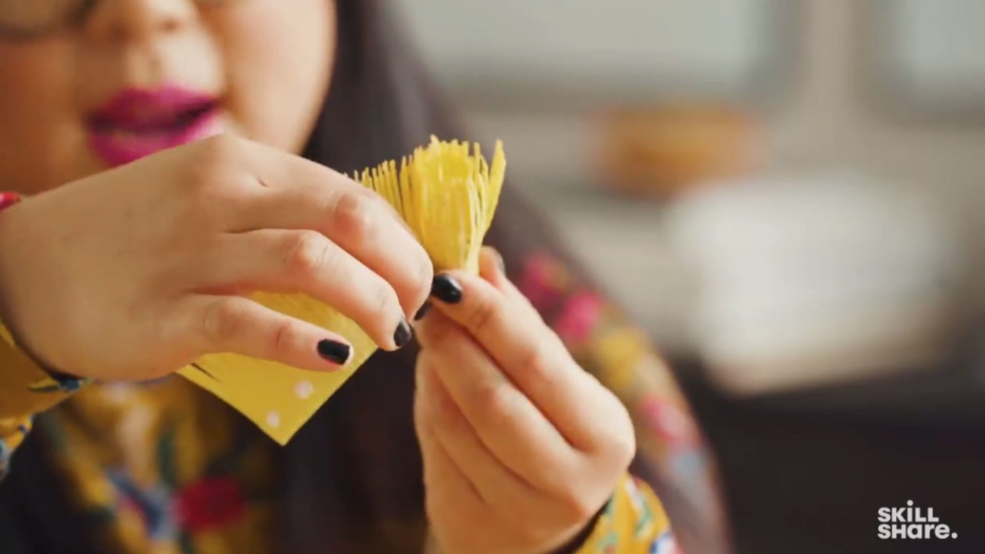 Person wrapping fringed crepe paper around a wire flower stem.