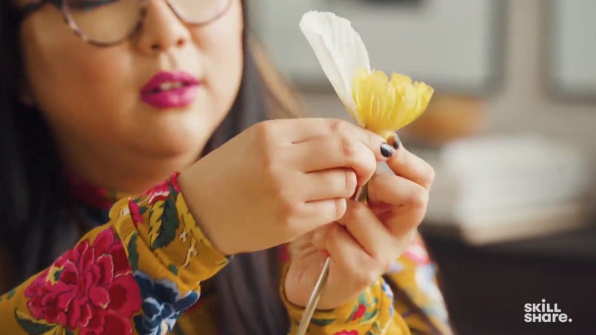 Crafter sticking paper flower petals onto a crepe paper and wire stem.