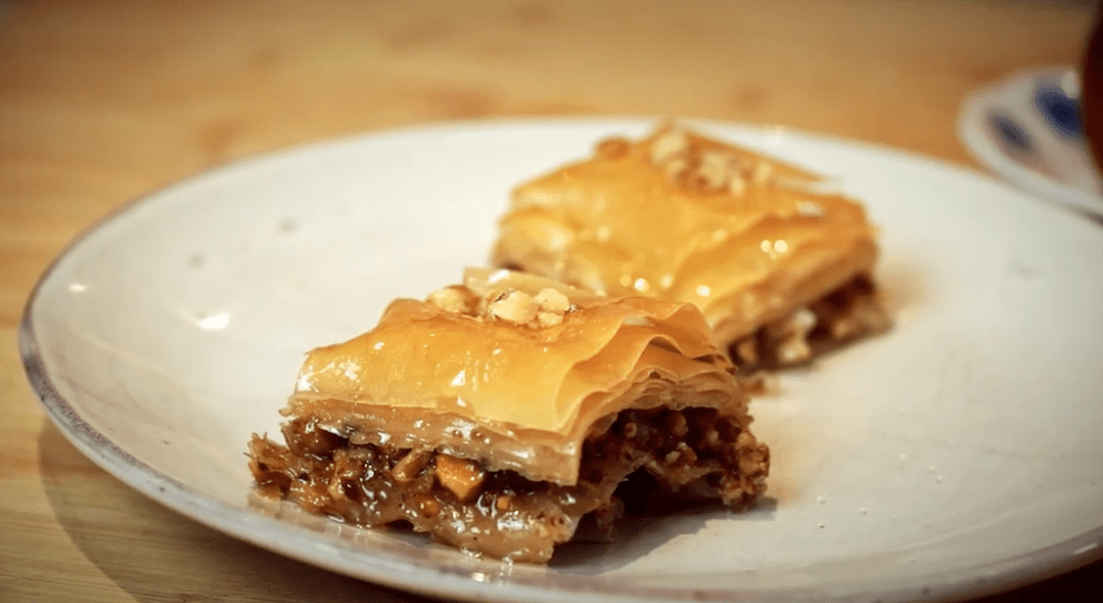 Two slices of baklava on a gray plate, ready to be eaten.