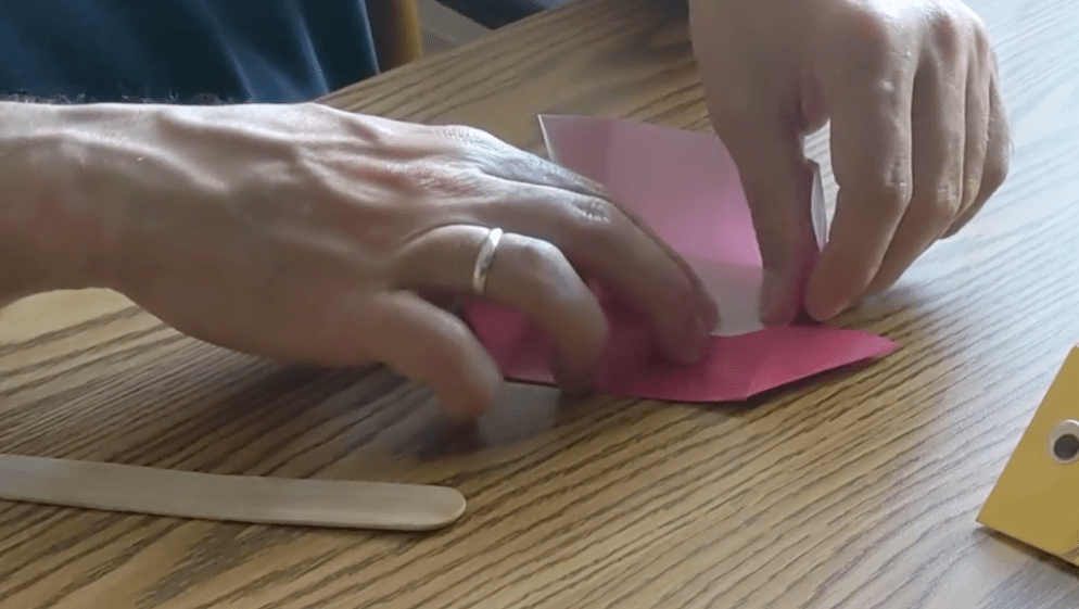 Origami paper is folded several times throughout the process to make a fish shape.
