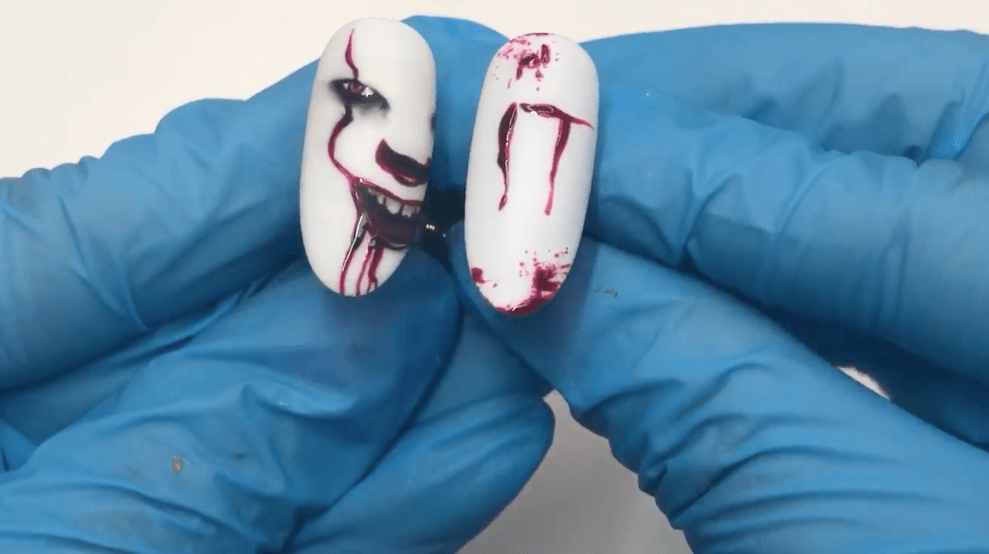 A detailed nail art design inspired by Stephen King’s “It” books, featuring the face of clown Pennywise.