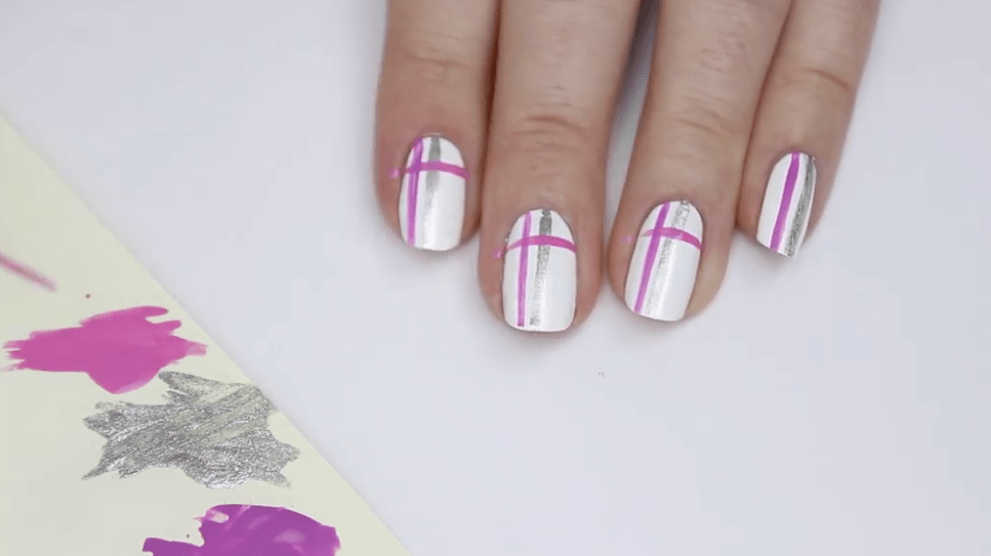 Easy nail art designs like these pink and silver lines on white painted nails are ideal for new artists to start with.