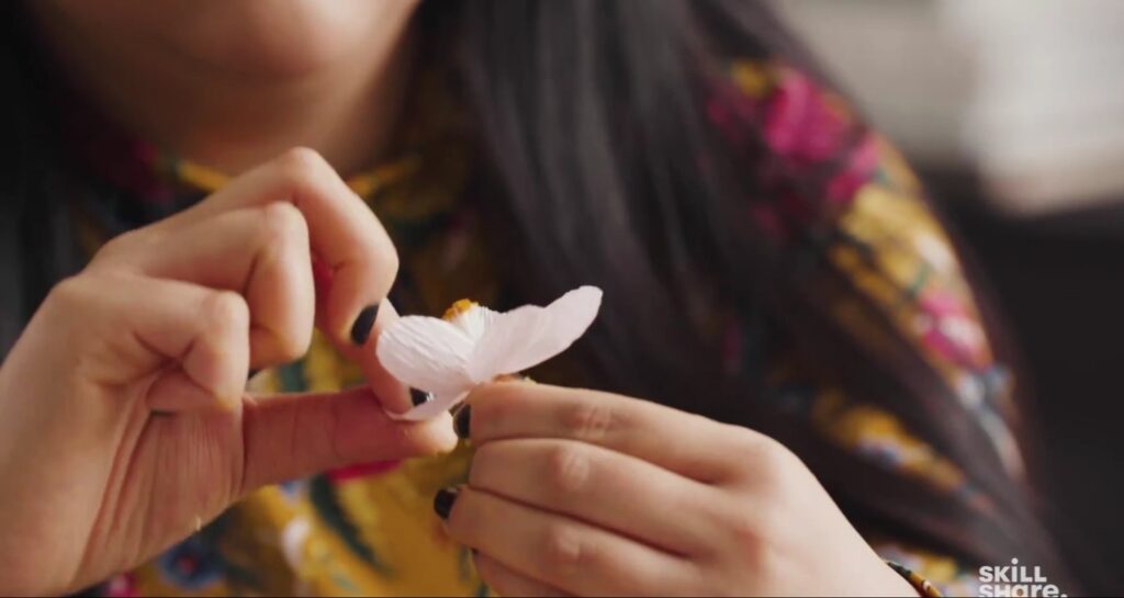An artist carefully opens the petals on a new crepe paper cherry blossom.
