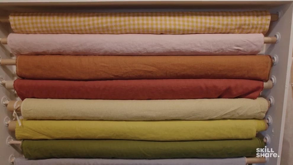 Several rolls of green, yellow, orange and pink fabrics are lined for sewing enthusiasts to choose from for their next project.