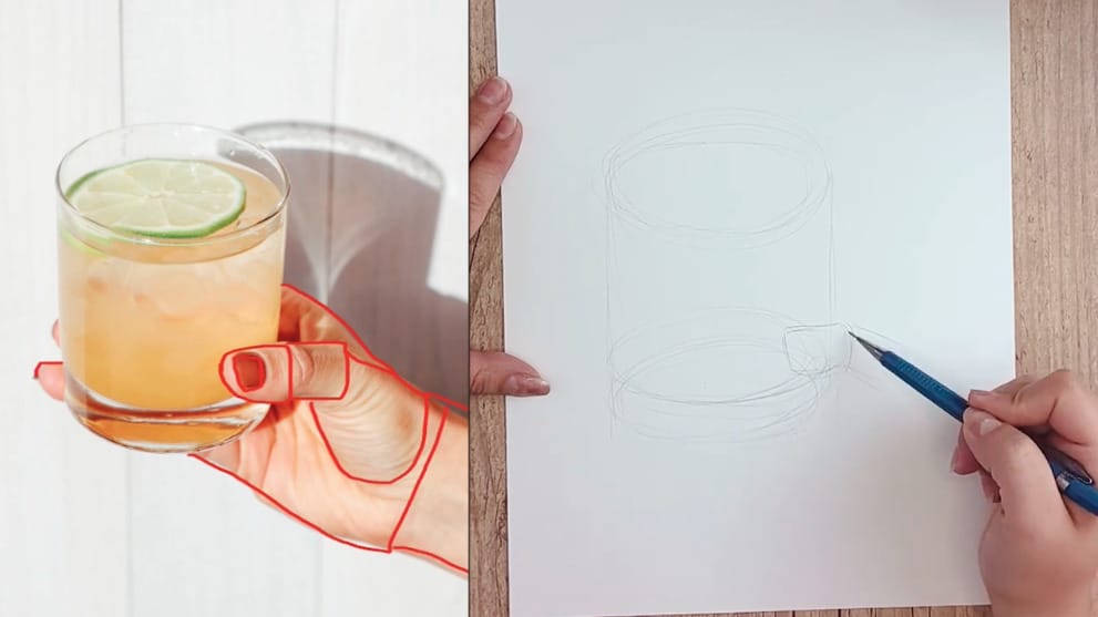 A reference picture of an orange drink with a lime slice in someone’s hand being drawn on paper with pencil.
