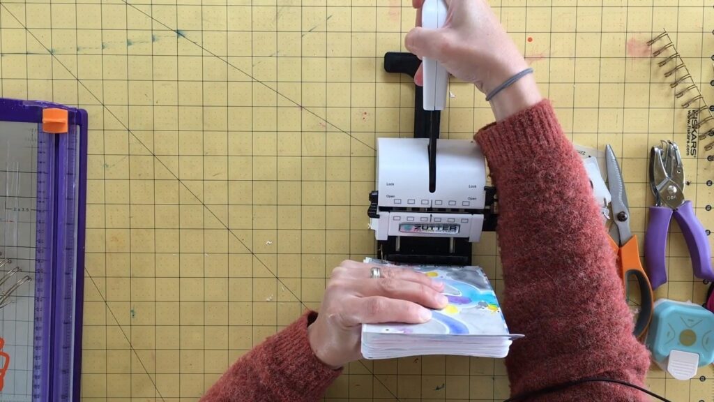 Skillshare teacher Nikki Jouppe using a binding machine to secure the coil that will hold together the pages of her art portfolio.