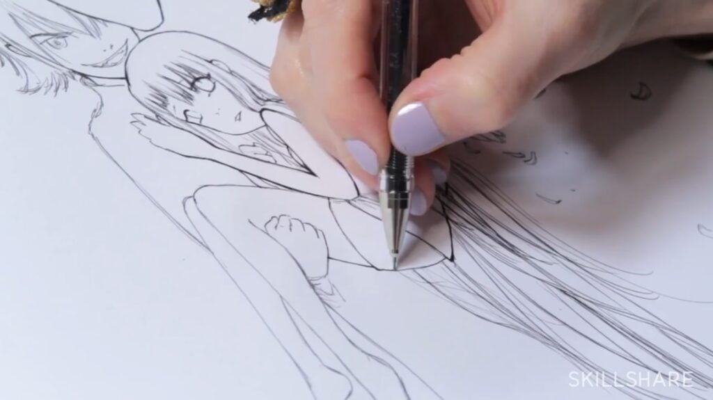 A person’s hand using a pen to ink over a pencil sketch on a white piece of paper. The sketch is drawn in manga style and portrays an angel sitting in the arms of a smiling character. 