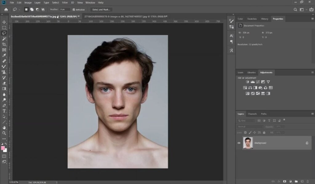 The photo editing software Photoshop open on a computer. The central workspace is occupied by a portrait of a man with dark brown hair staring directly into the camera.