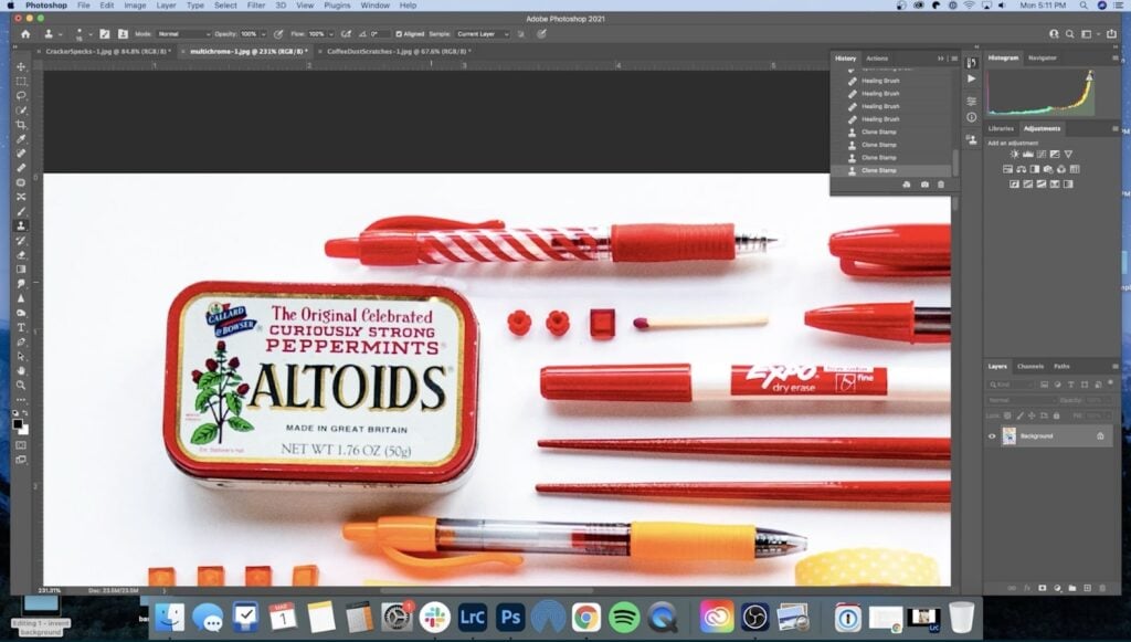 Photoshop is open to a photo with a variety of red and orange objects on a white background. Pens, an expo marker and an Altoids box are all among the varied objects. A very light white mark can be seen above the top right corner of the Altoids box. 