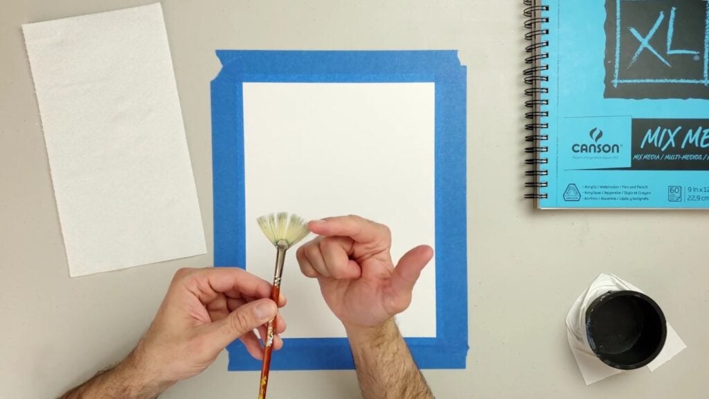 Artist holding a fan brush over their worktable