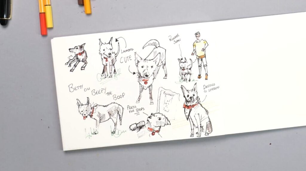 An open sketchbook laying on a gray tabletop. Its page is filled with drawings of the same dog in various poses.