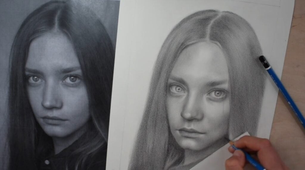 A person using a pencil to draw a realistic portrait of a woman with long straight hair. The reference photo of the woman is visible to the left.