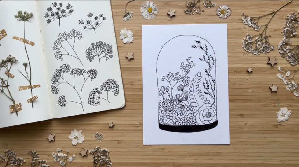A white piece of paper filled with an ink drawing of flowers and leaves in a bell jar.