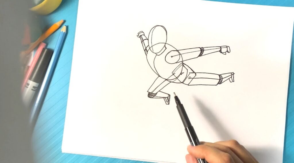 A person using a pen to sketch a human figure leaping toward the viewer, using perspective to make the pose believable.