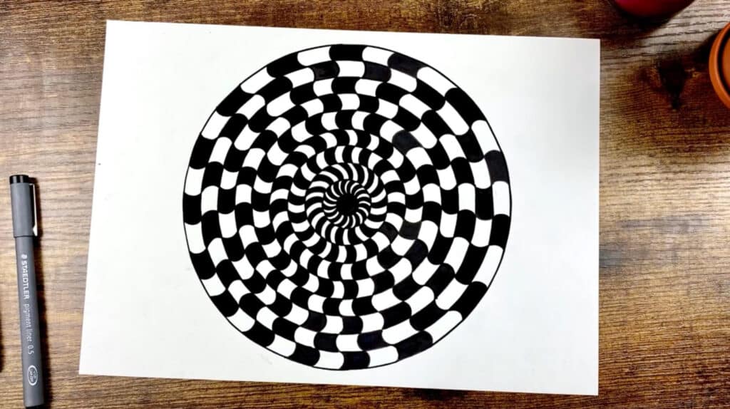 A black and white mandala drawn on a white piece of paper.  