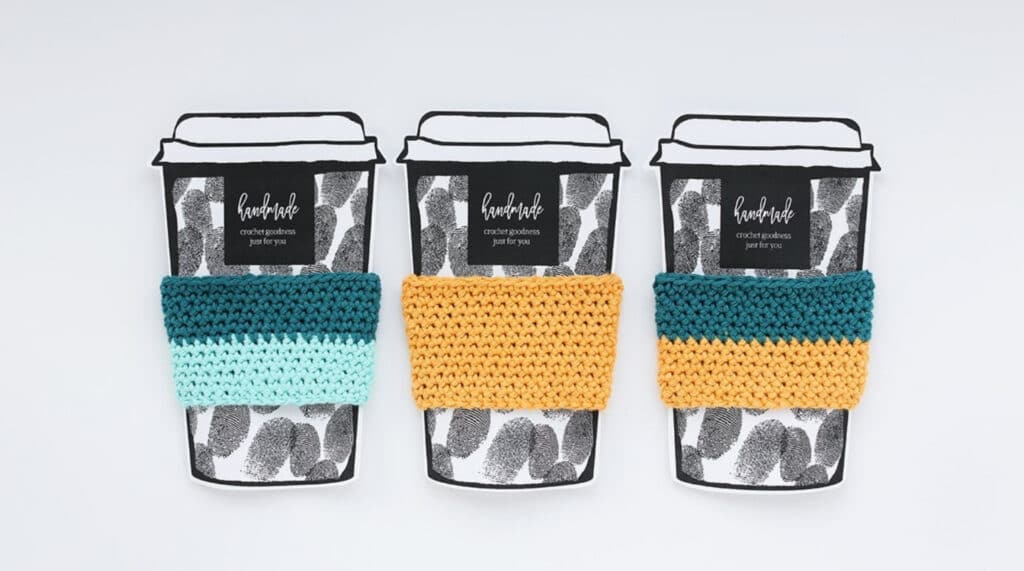 hree cup cozies arranged on top of illustrations of paper coffee cups. One is teal and light blue, one is yellow, and one is teal and yellow. 