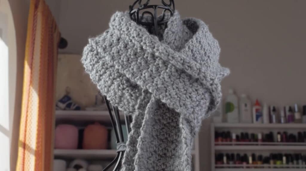 A gray scarf wrapped around the neck of a wrought iron mannequin. 