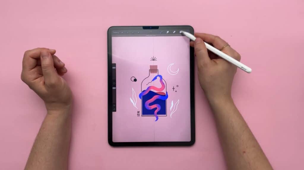 A person’s hand holding an Apple Pencil above an iPad. They’re using the iPad to create a drawing of a stoppered glass bottle against a pink background. There is a blue and pink gradient-toned snake wrapping around the bottle, and small white illustrations of a moon and plants around it. 