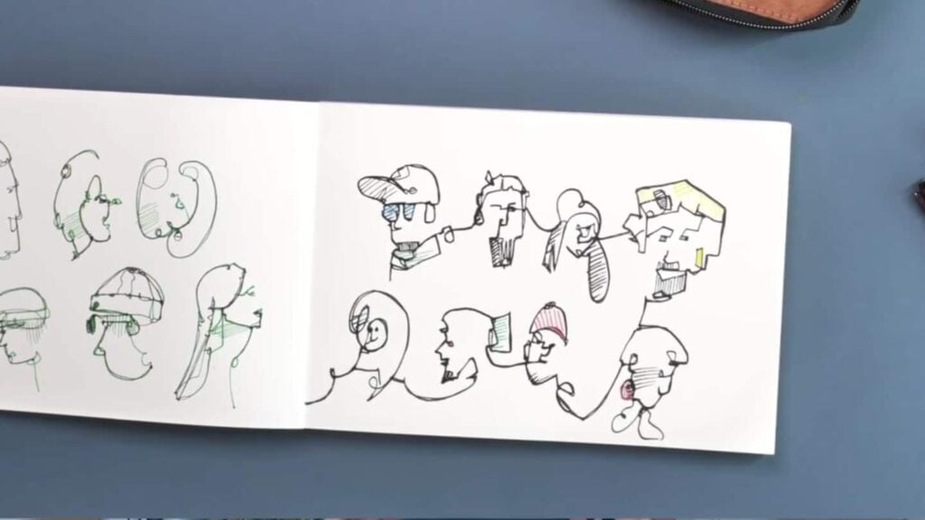 Open sketchbook on a blue work surface, featuring multiple human ink portraits, many from the same line and with pops of lined color on hats, glasses and hair