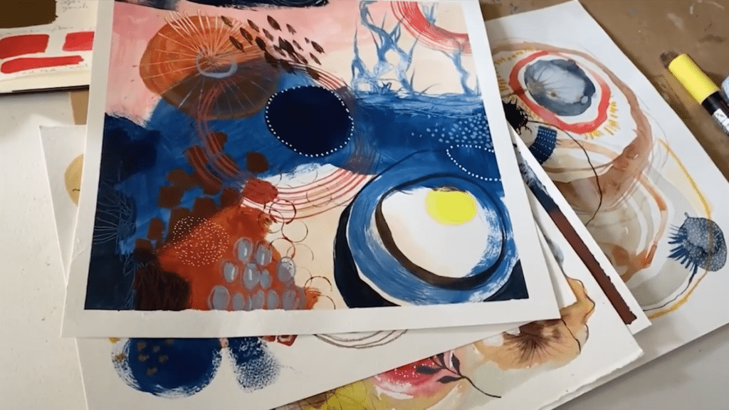 A stack of pages features vivid mixed media abstract paintings