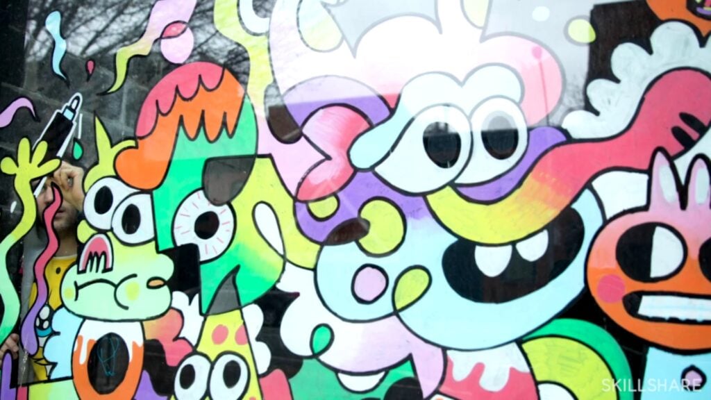 Doodle style, highly colorful painting on a glass window, featuring large, cartoonish faces mashed closely together, as if they’re in a crowd.