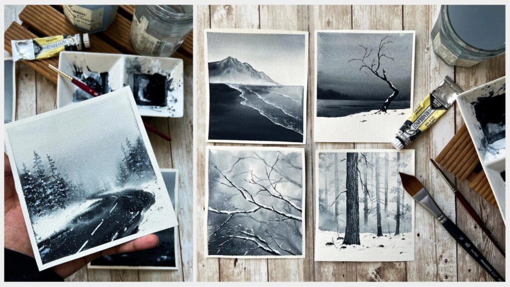 Two photos arranged side by side. The one on the left shows a person’s hand holding a square watercolor painting of a winding road cutting through a snowy winter forest. The one on the right shows four similar winter-themed paintings laid out on a wooden tabletop. All the paintings are painted in shades of gray.