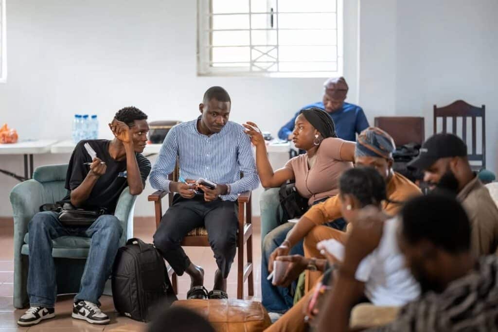 A group of students sits in a circle talking to one another. They are engaged in in-depth conversations, and are leaning closer to one another to hear each other better.
