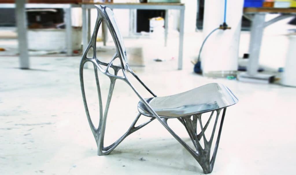 A cast metal chair which features sculpted supports that resemble bones or tendons. 